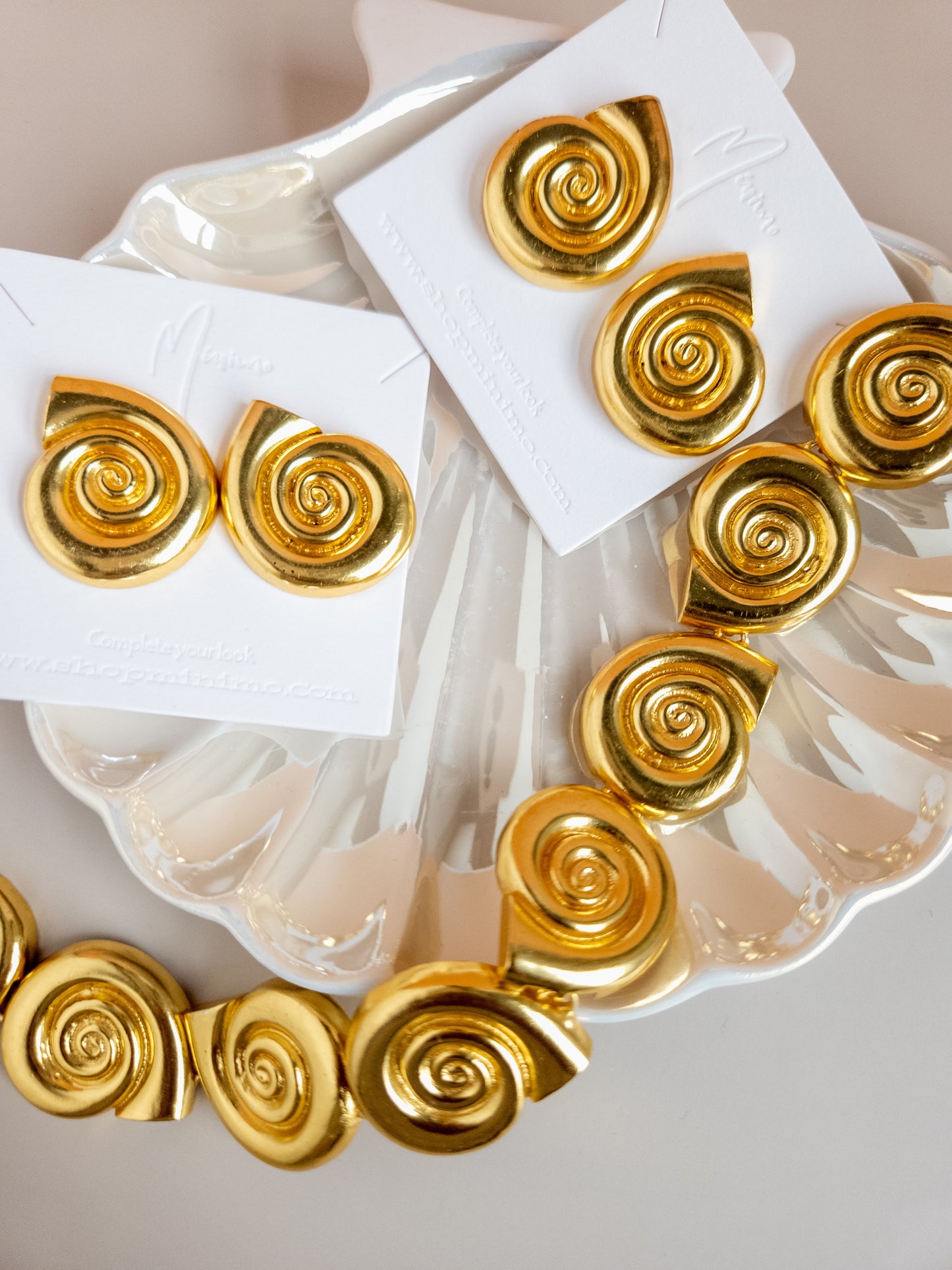 18k gold plated shell choker with spiral charms on a decorative shell plate.