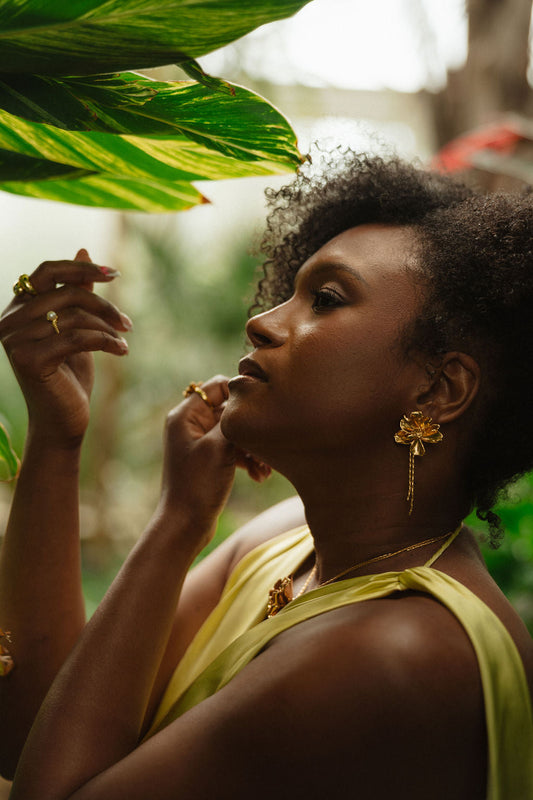 Falling Petals Bayahíbe Earrings with gold accents and bamboo chain tassels worn by a woman in a green dress.