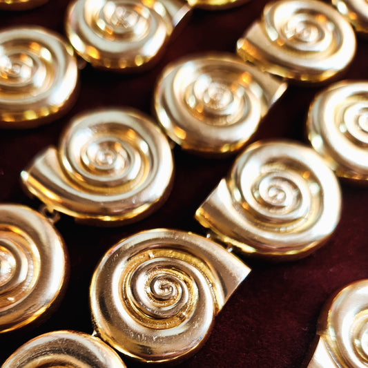 18k gold plated shell choker with spiral charms on dark background.
