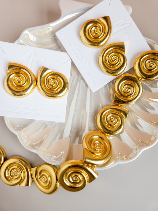 18k gold plated shell choker with spiral charms on a decorative shell plate.